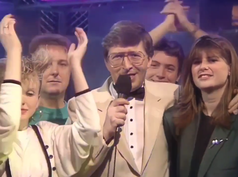 Simon Bates looking like he's a random dad at a wedding extending his arm to a young lady on Top of the Pops