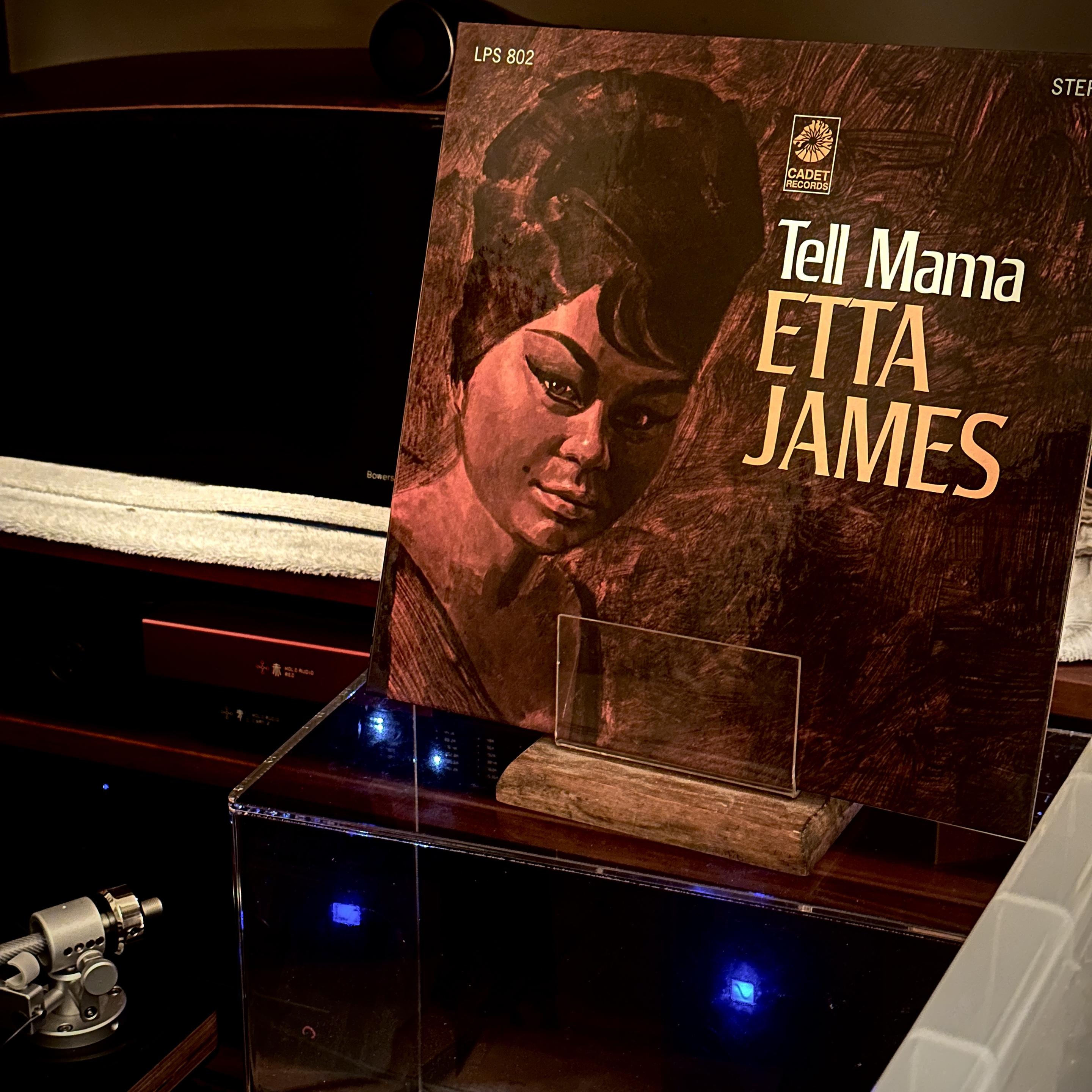 Photo of my Now Playing prop with Etta James’ ‘Tell Mama’ album in it. It shows a realistic painting of her bust in a beehive-ish tall wig, and slick, high-arched brows. The name/title lockup are on the right, with her 3/4 bust on the opposite side.