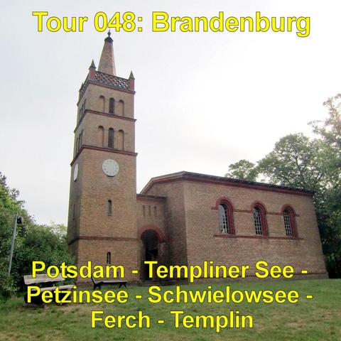 Eine kleine Backsteinkirche steht auf einer leicht erhöhten Rasenfläche. Der rechteckige Bau besitzt rundbogige Fenster mit dunklen Rahmen. An der Vorderseite ragt ein hoher, quadratischer Turm empor, der in eine schmale Spitze mit Kreuz übergeht. Eine runde Uhr ist in die Turmfassade eingelassen. Der Eingangsbereich liegt in einem bogenförmigen Durchgang unterhalb des Turms. Neben dem Gebäude stehen zwei einfache Holzbänke. Hohe Bäume umgeben die Kirche, ihre Kronen ragen in den hellen, leicht…
