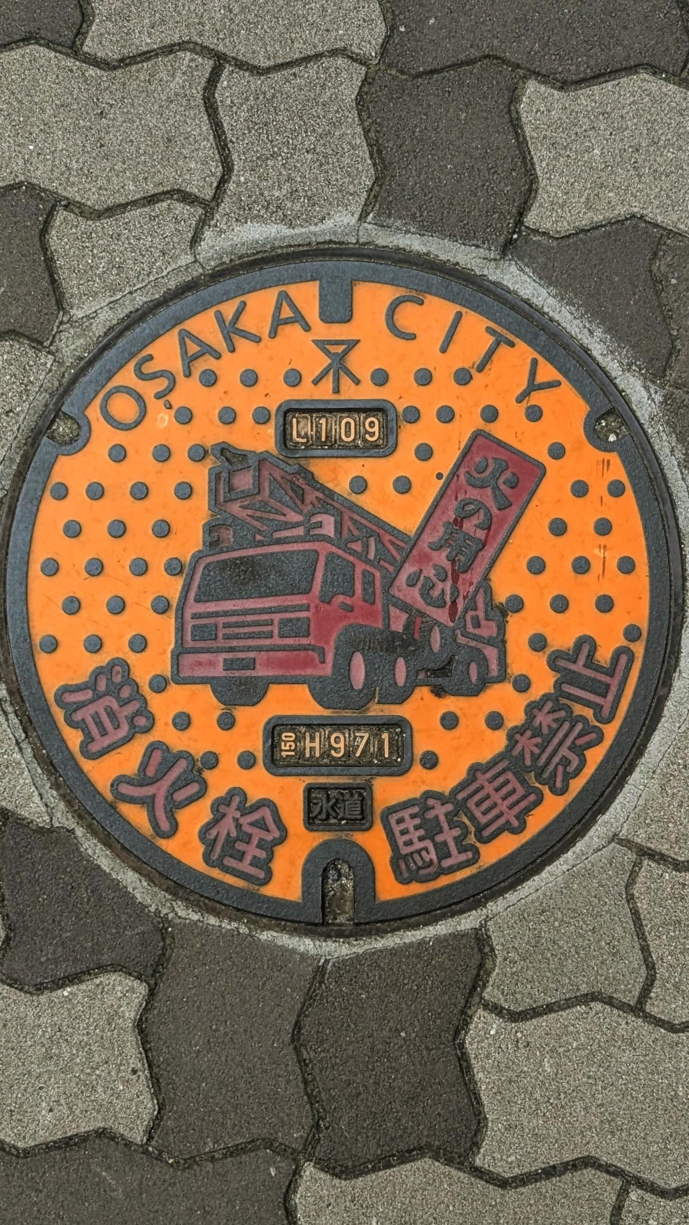 Colour photo of a very colourful manhole cover in Osaka, Japan of a fire engine.