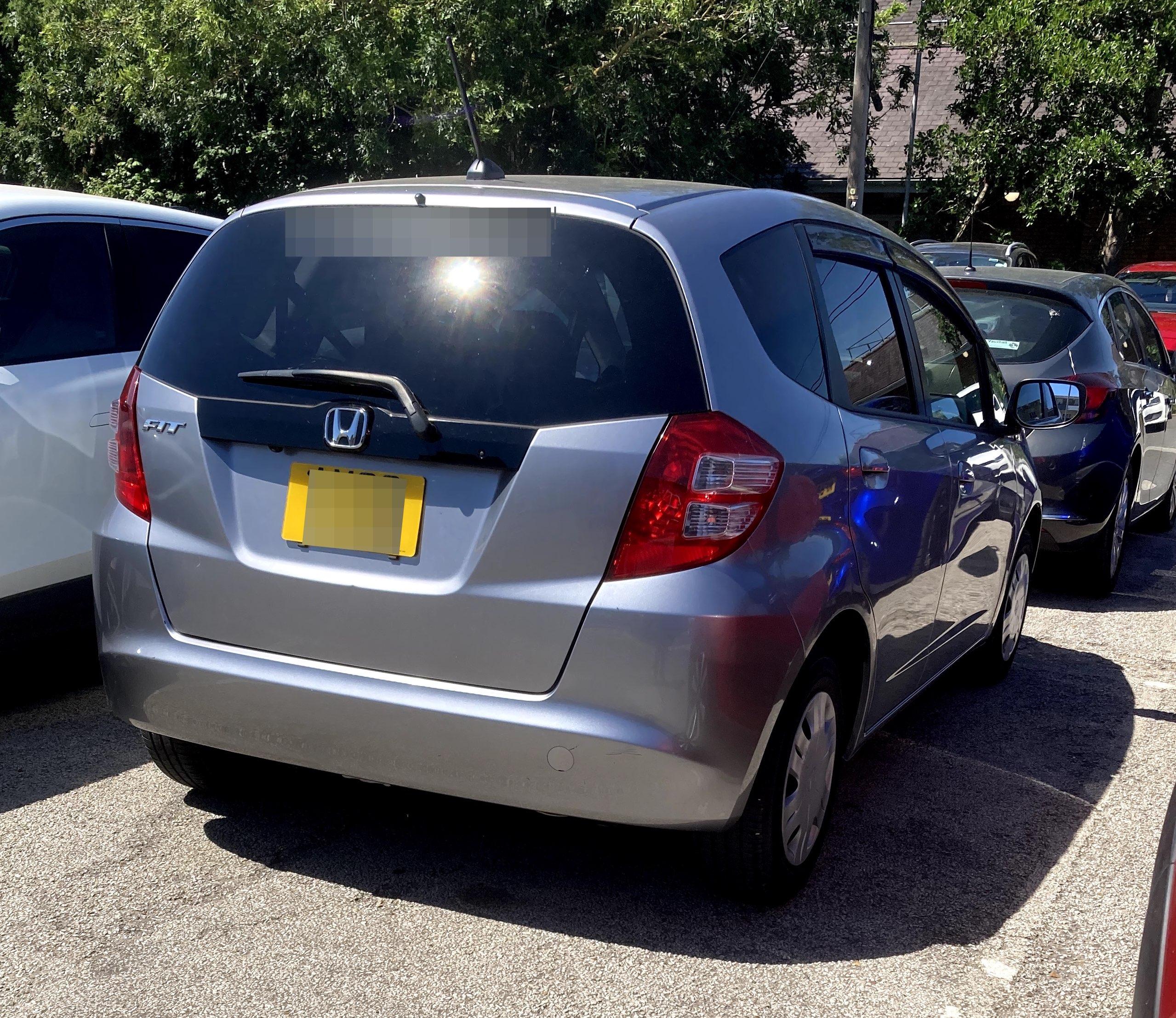 Silver second-generation Honda fit, rear quarter view.