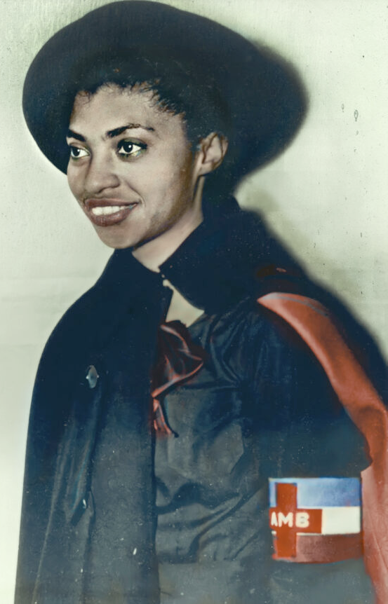 Colorized photo of Salaria Kee by Tina Paterson. In the photo Kee is facing to the left in 3/4 view. She has a broad brimmed hat and a red and black shawl.