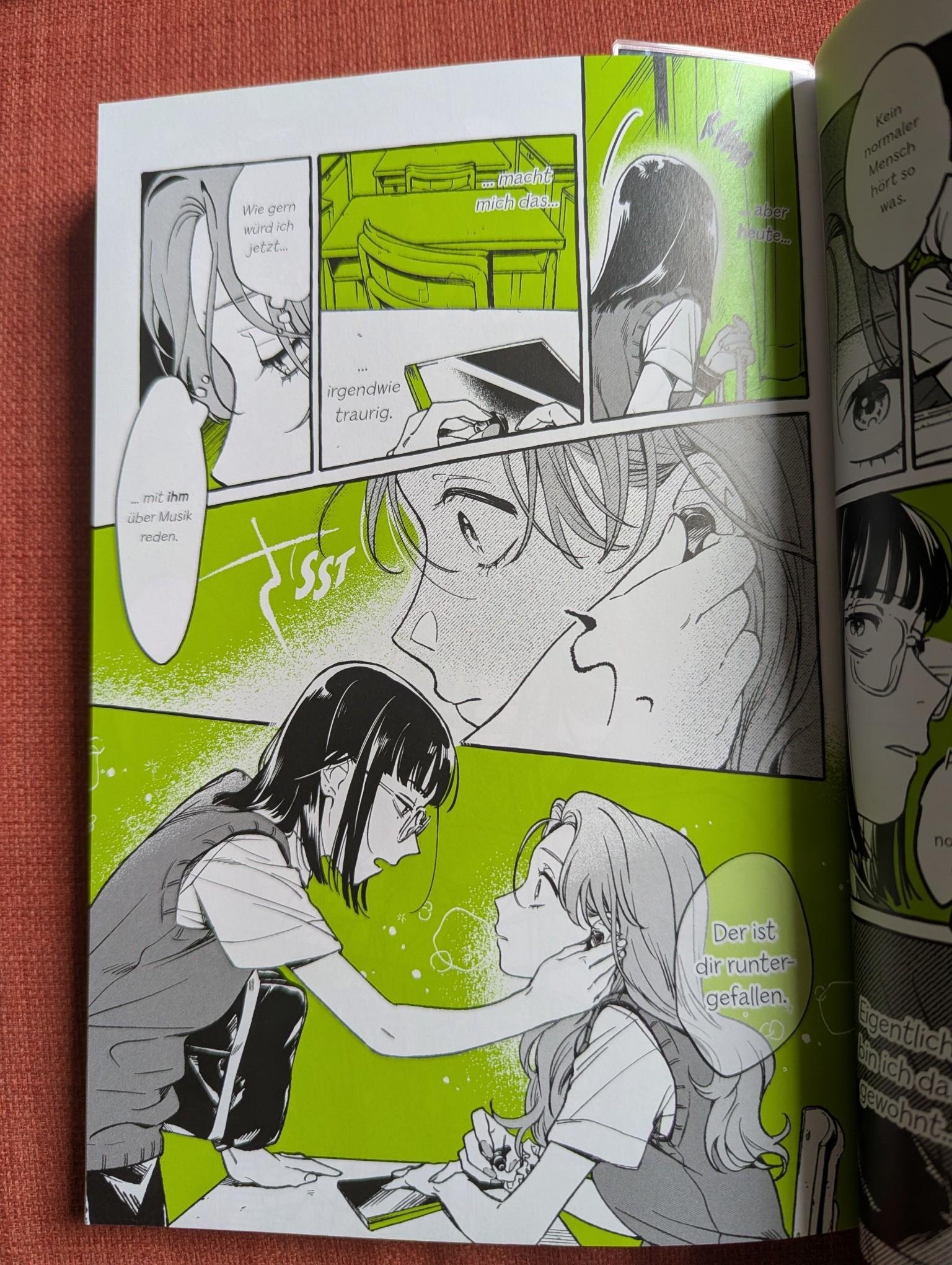 photo of a page from the manga. the text is in german. the drawings are gray, but the background colors are white against a neon green. the main panel is a black haired highschooler putting wireless headphones into the ear of a blonde student while saying "Der ist dir runter gefallen." translation: "you dropped this".