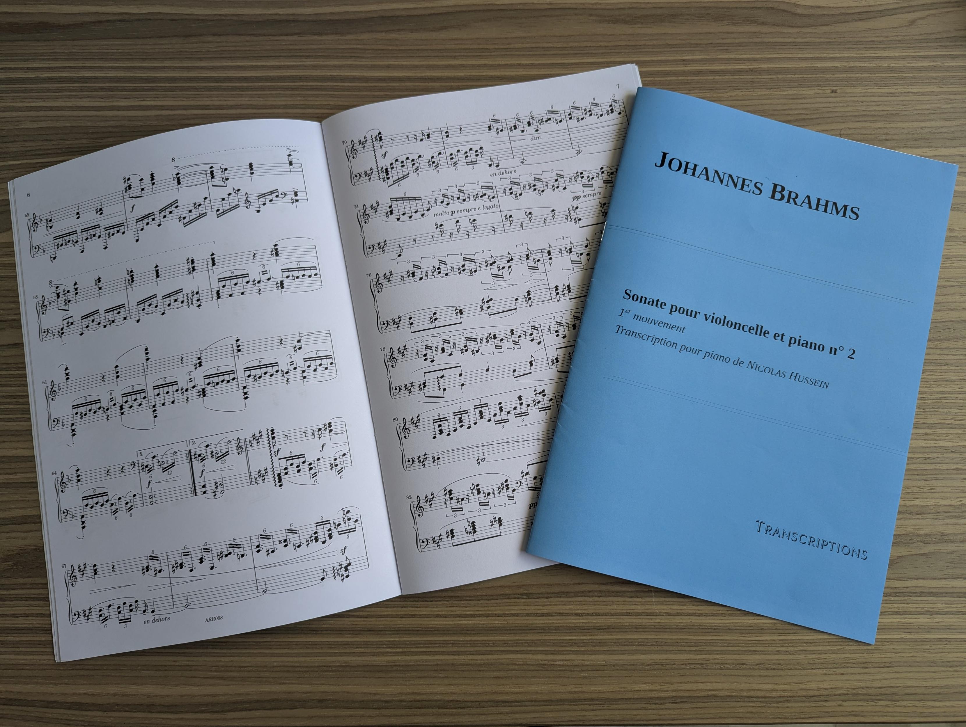 Deux partitions, l'une ouverte et l'autre fermée : Johannes Brahms, Sonate pour violoncelle et piano n° 2, 1er mouvement, transcription pour piano de Nicolas Hussein