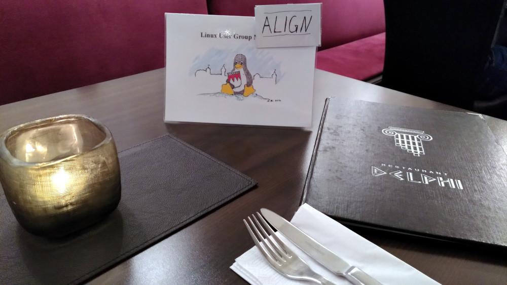 Foto: Auf einem Tisch befinden sich ein brennendes Teelicht in einem Glas, Essbesteck, unser Tischkarte mit dem Frankentux sowie eine Speisekarte mit dem Aufdruck "Delphi".