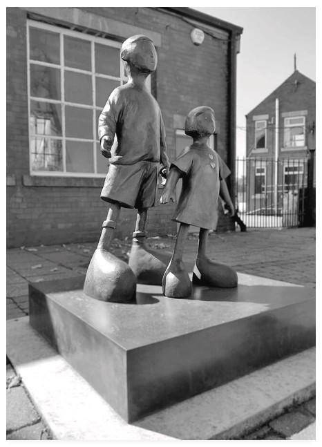 Black and white portrait photograph of a bronze sculpture of two children.
