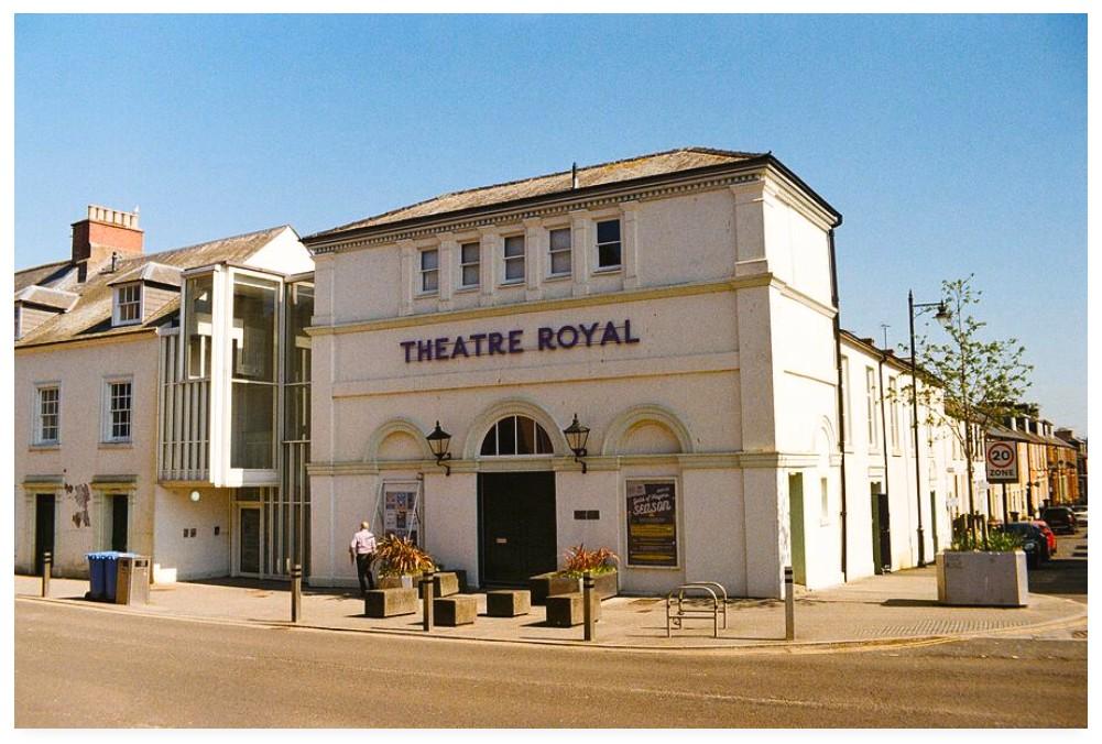 Colour film photograph of the Theatre Royal in Dumfries, Scotland.  An employee can be seen outside changing a playbill.