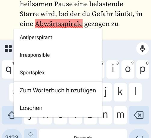 Ein Smartphone-Screenshot, der einen Texteingabebereich mit deutschem Text und eine teilweise verdeckte Bildschirmtastatur zeigt. Im Text ist das Wort „Abwärtsspirale“ mit einer roten Wellenlinie als vermeintlicher Rechtschreibfehler markiert. Ein geöffnetes Pop-up-Menü der Rechtschreibprüfung schlägt dafür völlig unpassende englische Wörter vor: „Antiperspirant“, „Irresponsible“ und „Sportsplex“. Darunter befinden sich die Standardoptionen „Zum Wörterbuch hinzufügen“ und „Löschen“. Die Leertas…