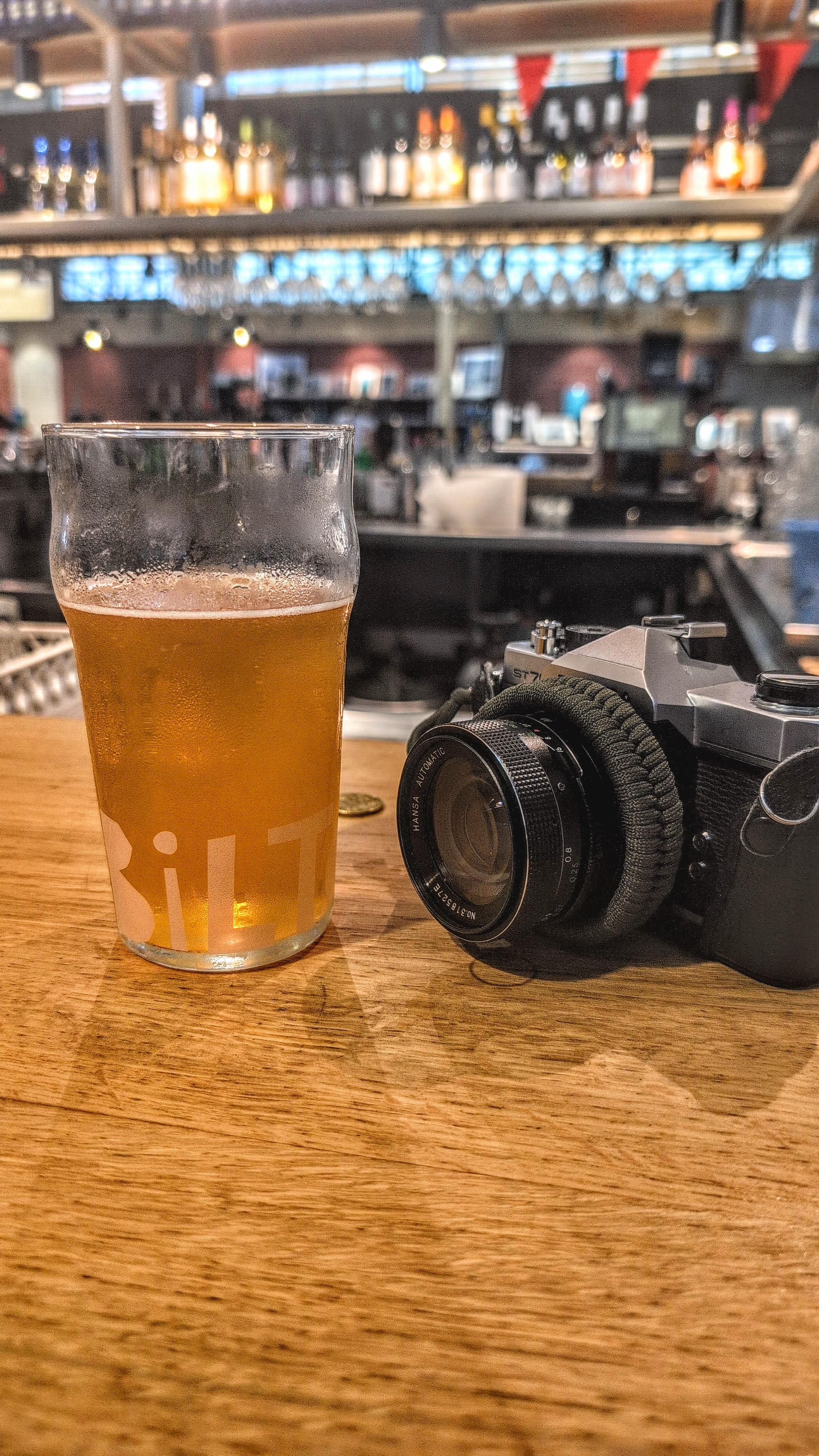 Colour photo of a glass of beer and a Fujica ST705, resting on the bar after a early morning 7 mile wander around Béziers, France. Taken in the market hall there earlier today.