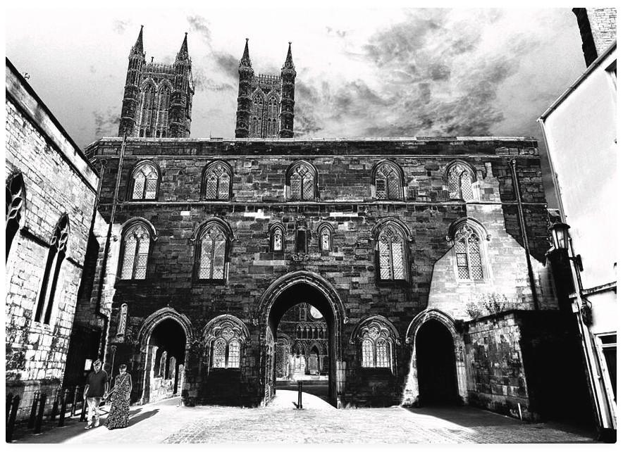 Darkly modified black and white photograph of a medieval arched entranceway to a cathedral.