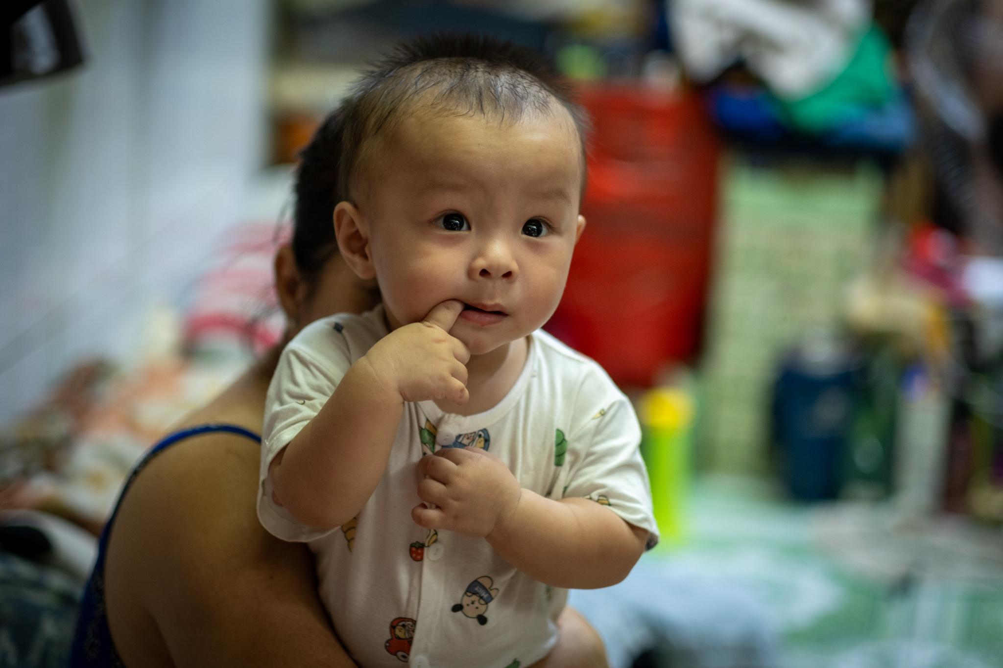 A baby boy is very curious about the people with the cameras.