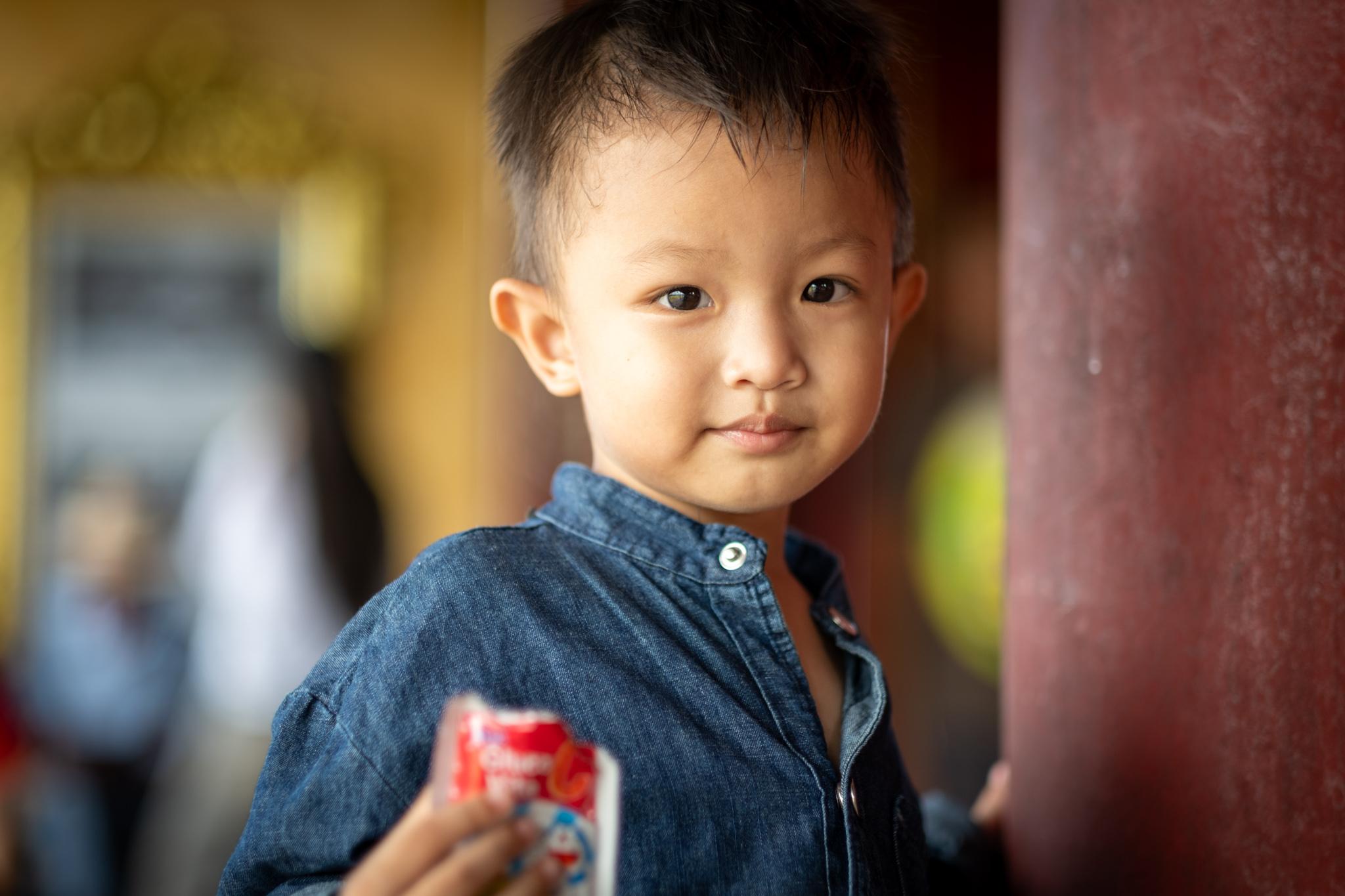 A young boy looks into the camera. Taken  at the Imperial City in Hue.