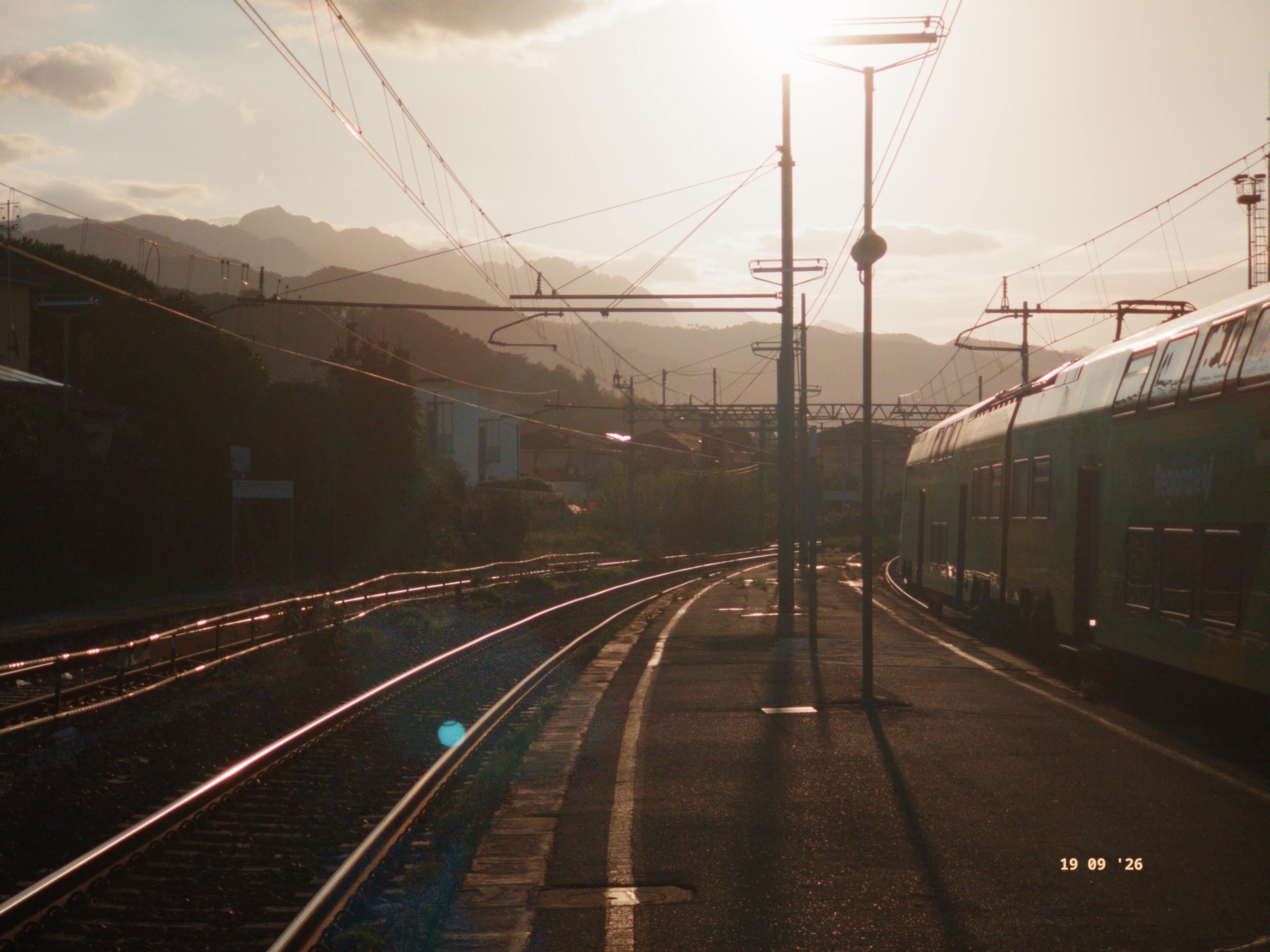 A picture of a train station during a sunrise.